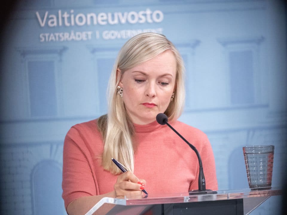 Maria Ohisalo at a Finnish Government press conference, the government's name on the wall behind her